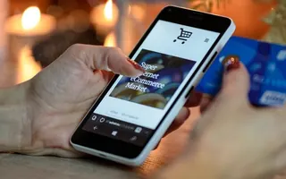 Hand using a smartphone checkout page with a bank card nearby